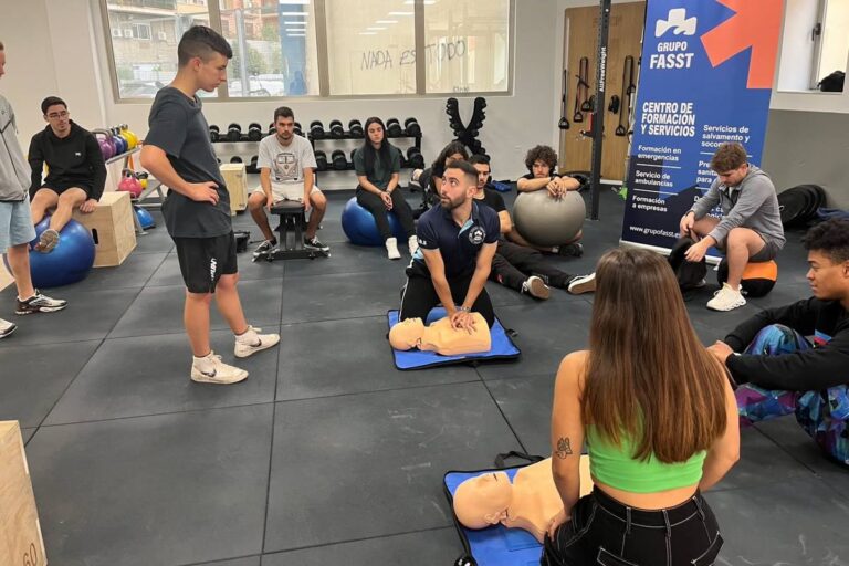 Instructor de Grupo FASST enseñando primeros auxilios con maniquíes a un grupo de alumnos