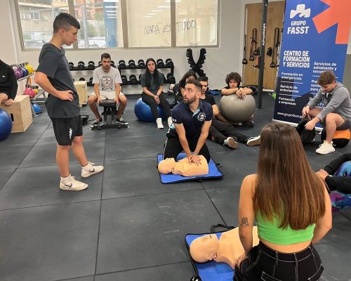 Instructor de Grupo FASST enseñando primeros auxilios con maniquíes a un grupo de alumnos