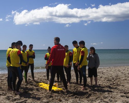 Instructor de Grupo FASST explicando a alumnos de socorrismo cómo atender a una víctima en la playa